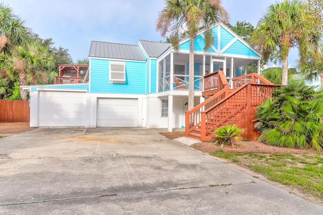 view of front of home featuring concrete driveway, stairway, a sunroom, metal roof, and a garage