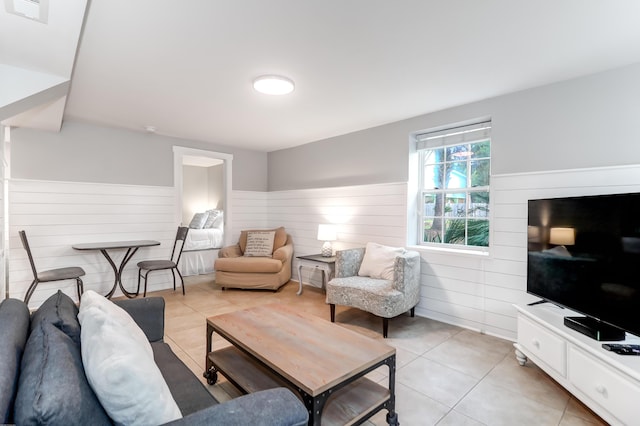 living area featuring a wainscoted wall, light tile patterned flooring, and visible vents