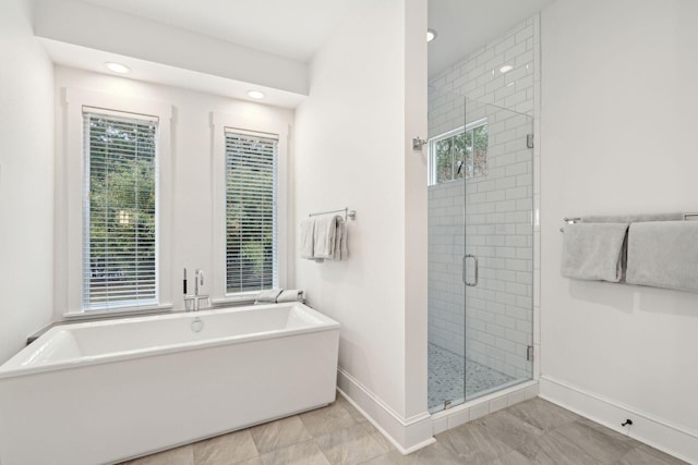 bathroom featuring recessed lighting, a stall shower, a soaking tub, and baseboards