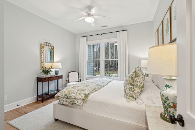 bedroom with ceiling fan, wood finished floors, visible vents, and baseboards