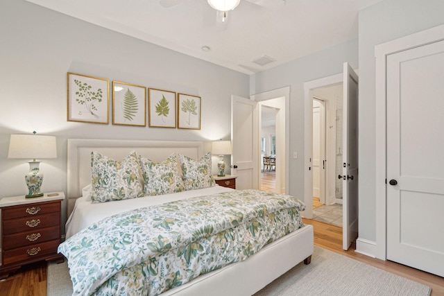 bedroom with ceiling fan, visible vents, and wood finished floors