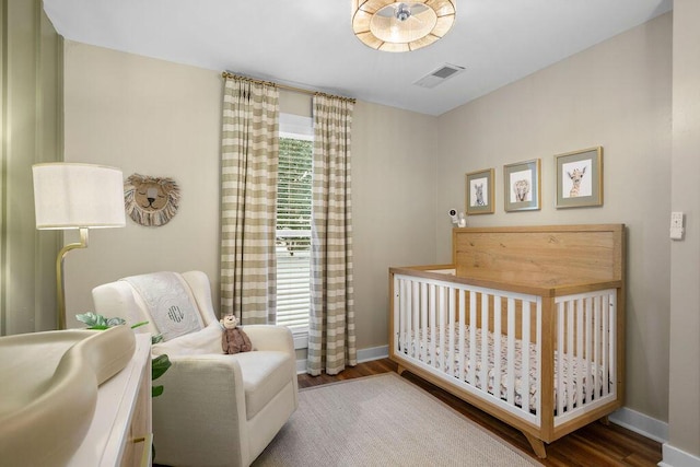 bedroom with a nursery area and hardwood / wood-style floors