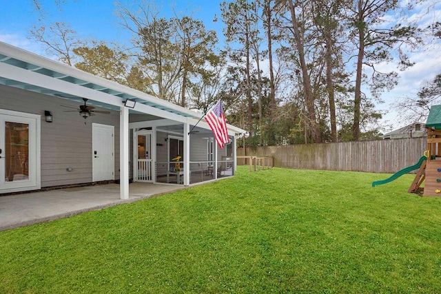 view of yard with ceiling fan, a sunroom, a playground, and a patio