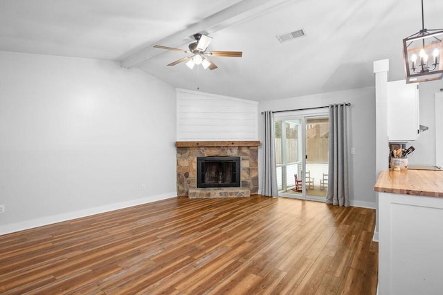 unfurnished living room with hardwood / wood-style flooring, a fireplace, ceiling fan with notable chandelier, and lofted ceiling with beams