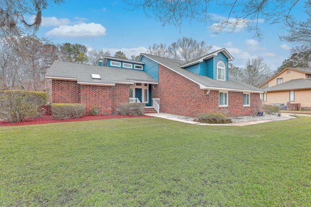 view of front of property with a shingled roof, a front yard, and brick siding