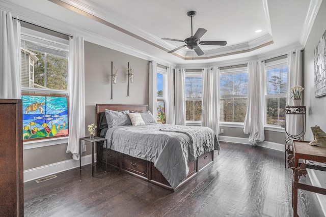 bedroom featuring multiple windows, crown molding, dark hardwood / wood-style flooring, and a tray ceiling