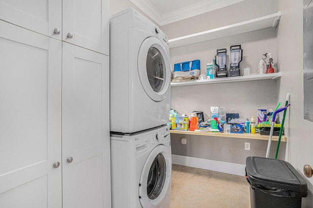 clothes washing area with stacked washer / drying machine, crown molding, and cabinets