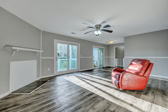 living area featuring ceiling fan, wood finished floors, visible vents, and baseboards