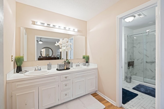 full bathroom with double vanity, a sink, and a marble finish shower