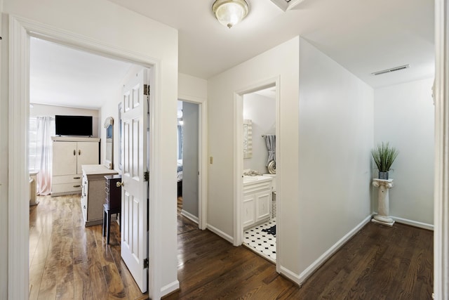 hall with dark wood-style floors, baseboards, and visible vents