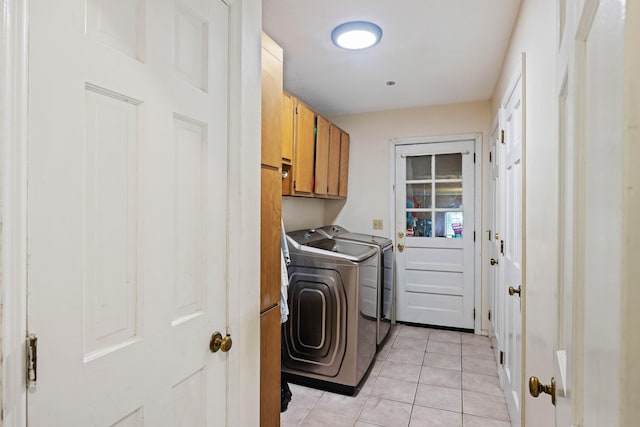 laundry room with cabinet space, light tile patterned floors, and washer and clothes dryer
