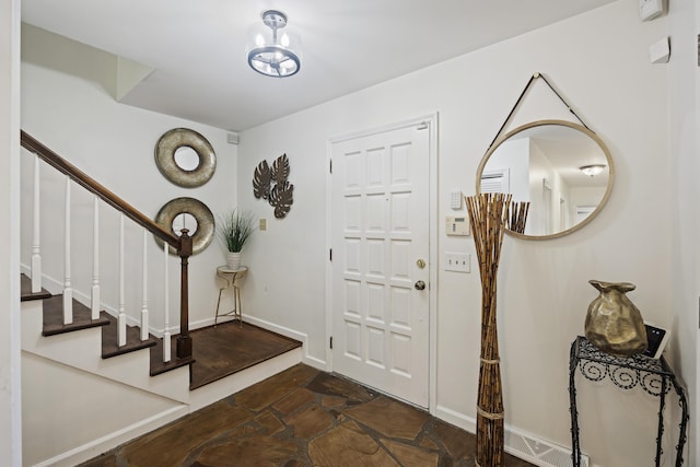 entryway featuring stairs, stone finish floor, baseboards, and an inviting chandelier