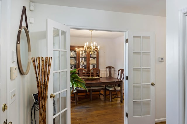 dining area featuring french doors, an inviting chandelier, and wood finished floors