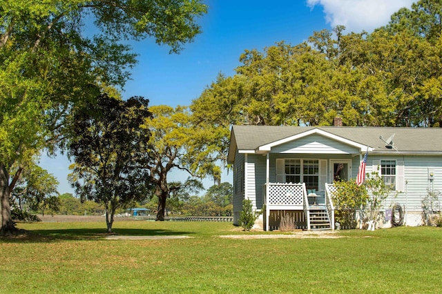 rear view of property with covered porch, a yard, and a chimney