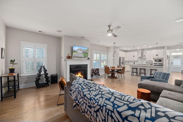 living room with light wood-type flooring, ceiling fan, and a wealth of natural light