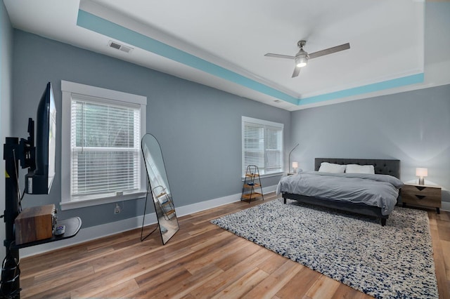 bedroom with ceiling fan, hardwood / wood-style flooring, and a tray ceiling