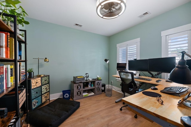 home office featuring light wood-type flooring, ceiling fan, and a wealth of natural light