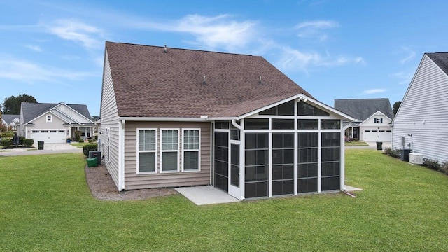 back of property with a sunroom, a yard, and a garage