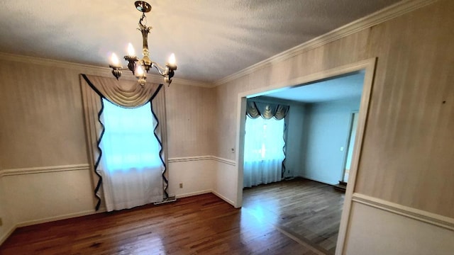 spare room with baseboards, crown molding, an inviting chandelier, and wood finished floors