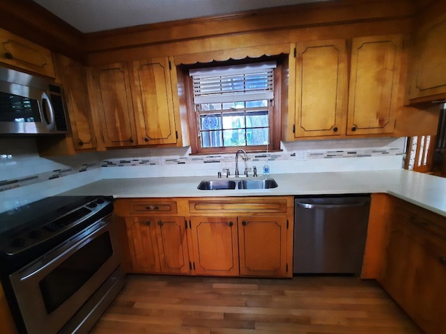 kitchen featuring light countertops, wood finished floors, appliances with stainless steel finishes, and a sink