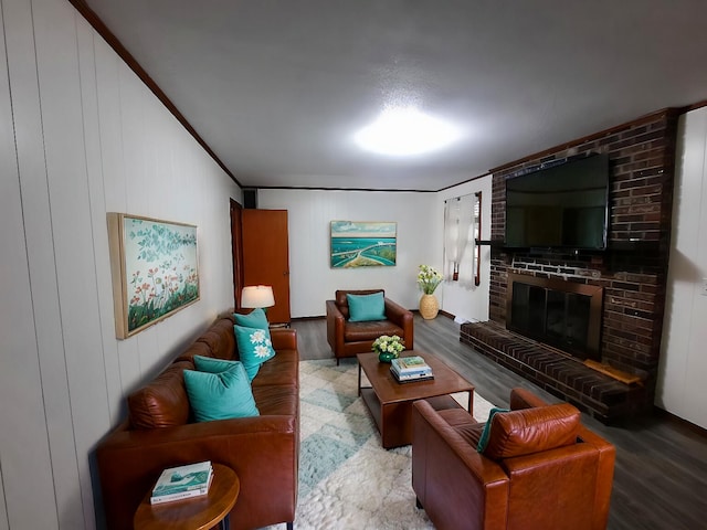 living room with a brick fireplace, wood finished floors, and ornamental molding