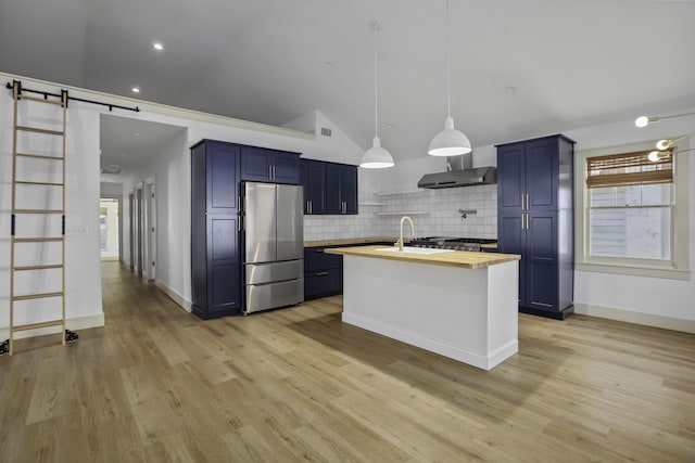 kitchen with wood counters, vaulted ceiling, decorative backsplash, stainless steel fridge, and a barn door