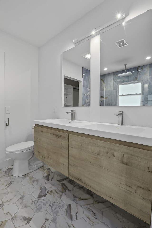 bathroom with tiled shower, vanity, and toilet