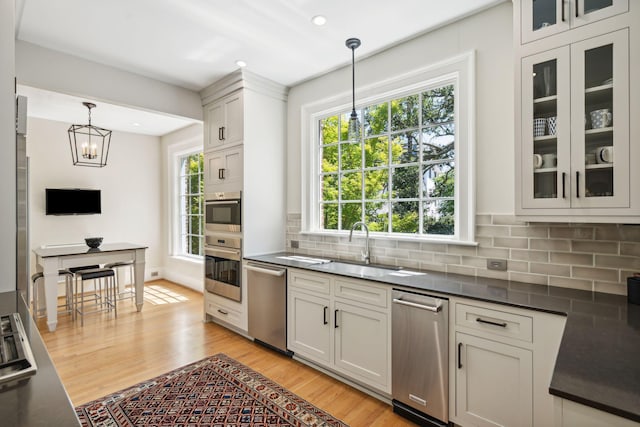 kitchen with dishwasher, pendant lighting, decorative backsplash, sink, and light wood-type flooring