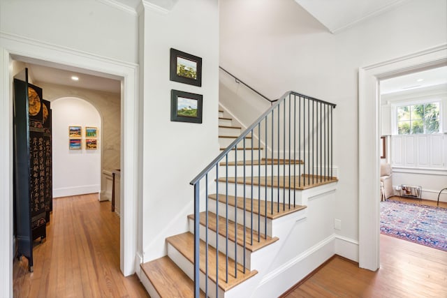 stairway with hardwood / wood-style floors and ornamental molding