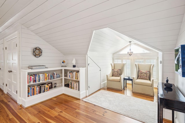 living area featuring wood-type flooring, wood walls, and vaulted ceiling