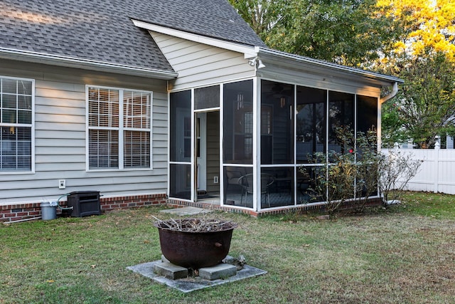 rear view of house with a lawn, a sunroom, and central AC unit