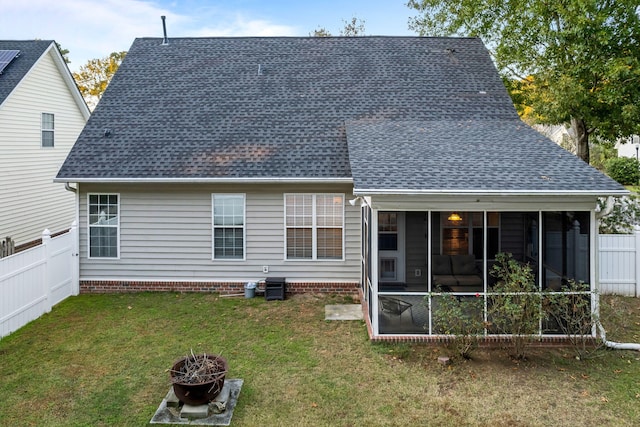 back of house featuring an outdoor fire pit, a lawn, and a sunroom