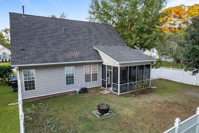 back of property with an outdoor fire pit, a yard, and a sunroom