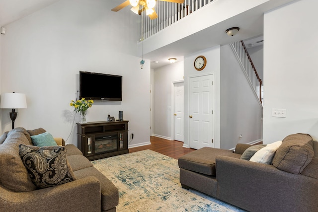 living room featuring a high ceiling, ceiling fan, and hardwood / wood-style flooring