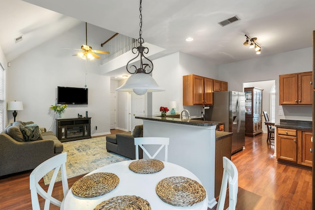 kitchen featuring ceiling fan, dark wood-type flooring, decorative light fixtures, high vaulted ceiling, and stainless steel fridge with ice dispenser