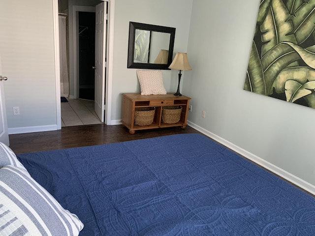 bedroom featuring ensuite bath, baseboards, and wood finished floors