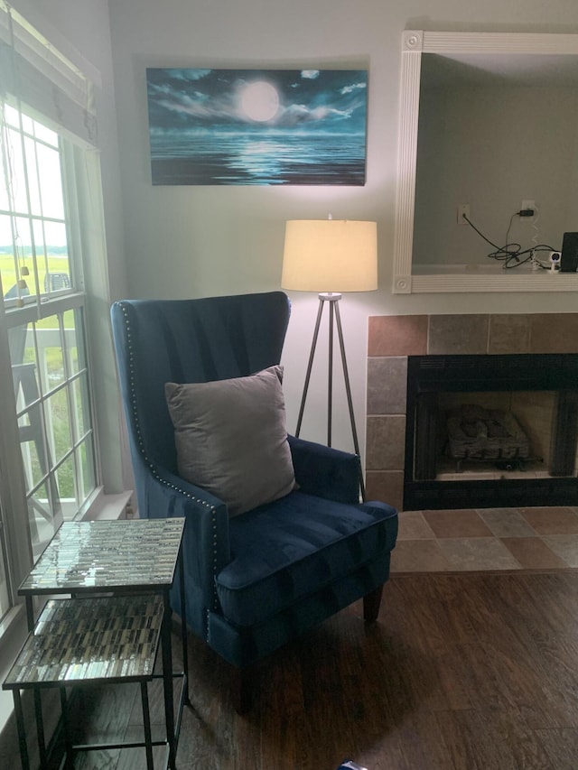 living area with a tile fireplace and wood finished floors
