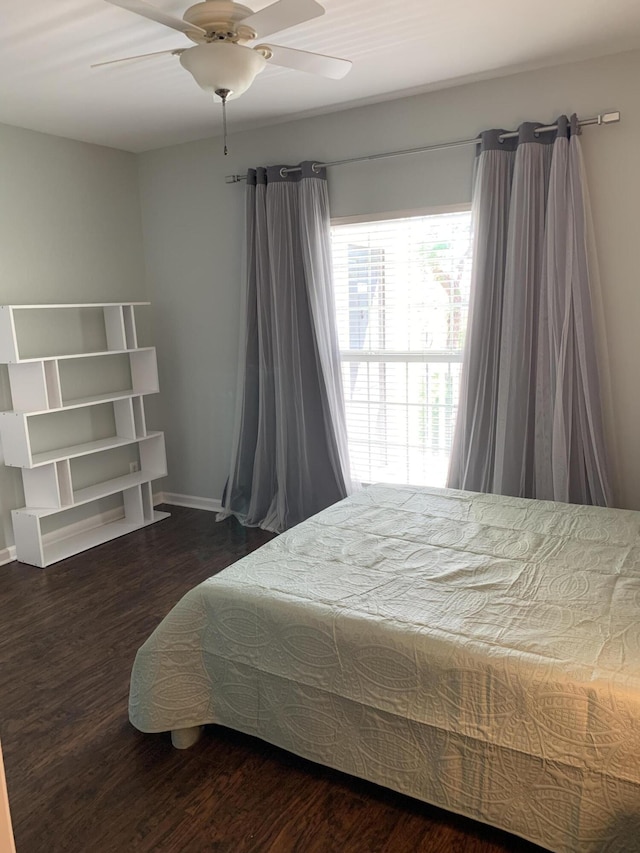 bedroom with a ceiling fan, baseboards, and wood finished floors