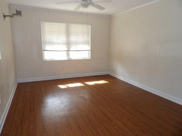 empty room featuring ornamental molding, dark hardwood / wood-style floors, and ceiling fan