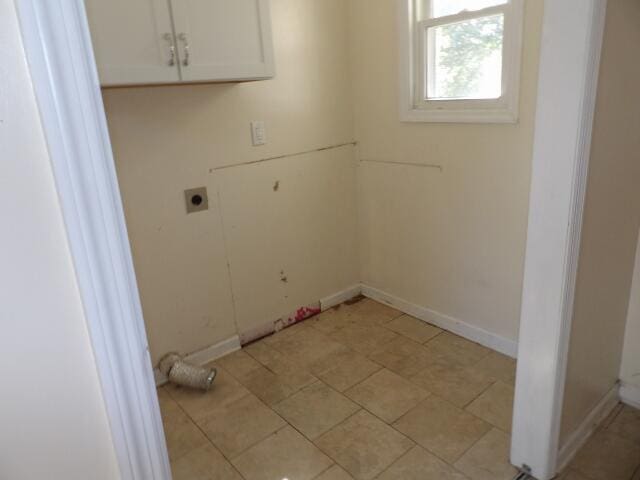 laundry area with hookup for an electric dryer, light tile patterned floors, and cabinets