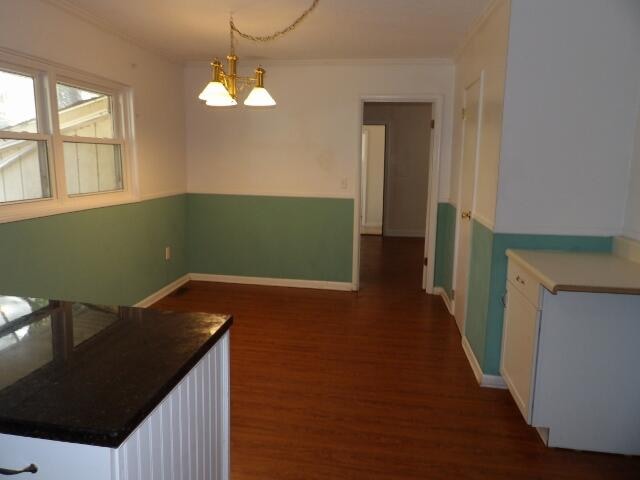 dining space with dark wood-type flooring, a notable chandelier, and crown molding