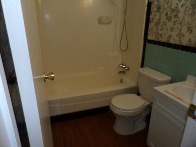 full bathroom featuring toilet, shower / bath combo with shower curtain, wood-type flooring, vanity, and tile walls