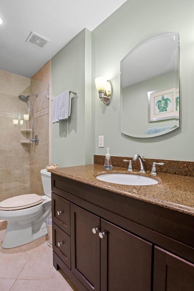 bathroom featuring tile patterned floors, toilet, vanity, and a tile shower