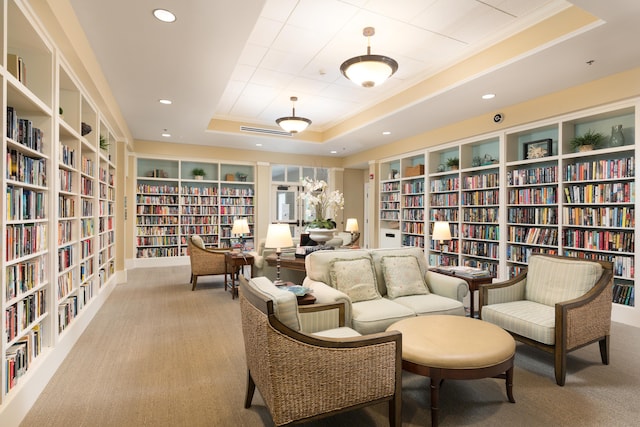 living area featuring light carpet, built in features, and a tray ceiling