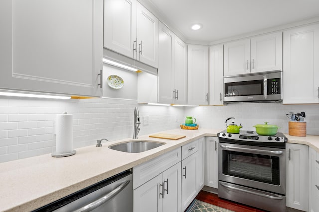 kitchen with white cabinetry, stainless steel appliances, backsplash, light stone counters, and sink