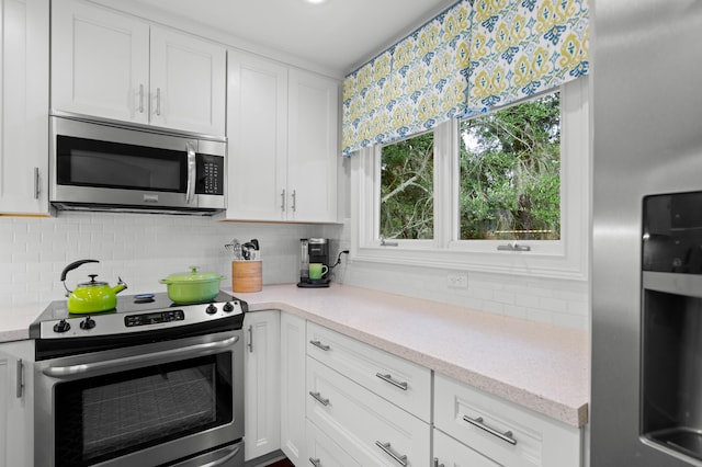 kitchen featuring decorative backsplash, light stone counters, stainless steel appliances, and white cabinetry