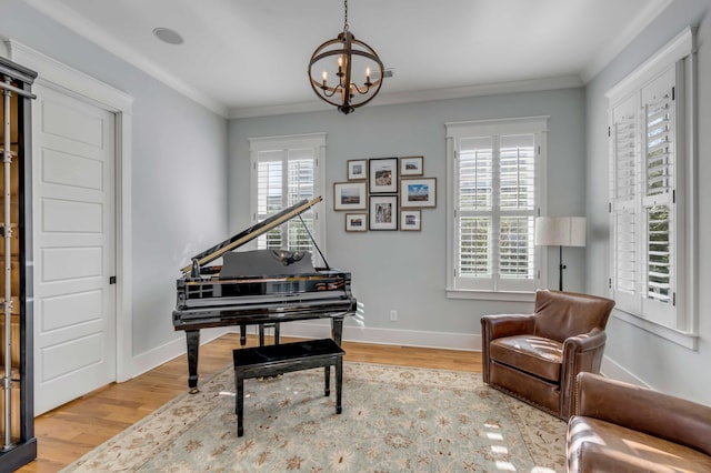 living area with baseboards, ornamental molding, a chandelier, and wood finished floors