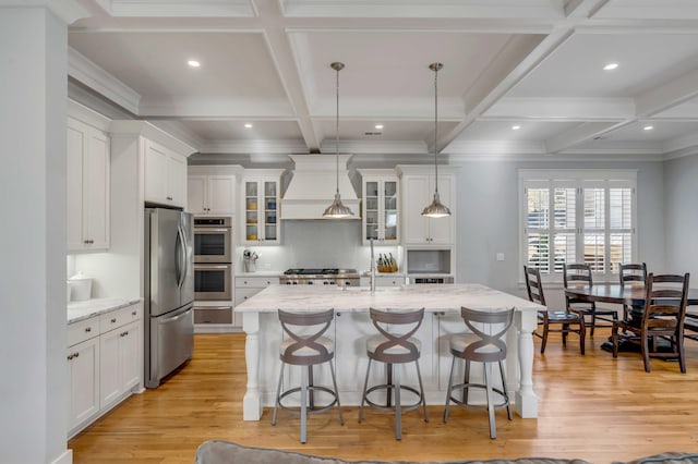 kitchen with light wood-style flooring, appliances with stainless steel finishes, custom exhaust hood, and white cabinets