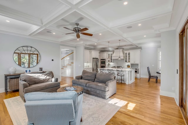 living area featuring stairs, coffered ceiling, and light wood-style flooring