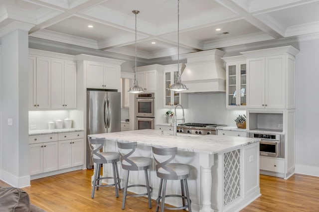 kitchen featuring white cabinets, a kitchen island with sink, custom exhaust hood, stainless steel appliances, and light wood-type flooring